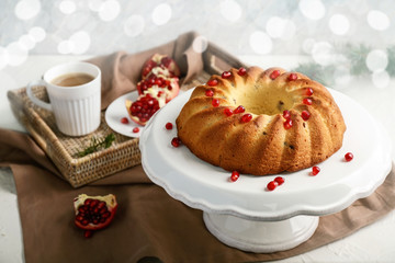 Stand with delicious Christmas cake and cup of coffee on white table