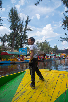 ni&ntilde;o de pie sobre lancha trajinera en xochimilco mexico