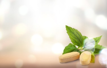 Organic pills with mint leaves on  background