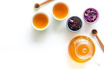 Tea in pot and cups with dry leaves on white background top view mock up