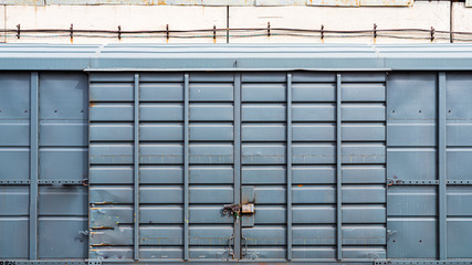 old metal door with a large padlock in a warehouse, garage. Front view of a blue container