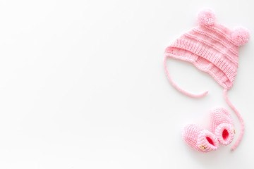 Knitted pink footwear and hat for baby on white background top view mockup