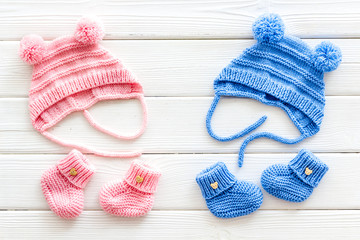 Booties and hat for newborn boy and girl on white wooden background top view