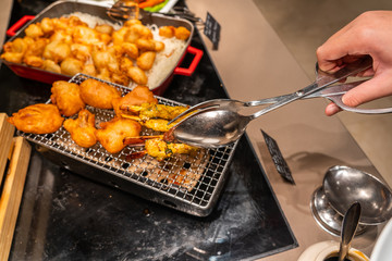 Human hand picking fried chicken stick in buffet restaurant