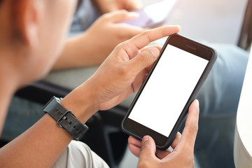 Cropped shot view of man hands holding smart phone with blank copy space screen for your text message or information content, female reading text message on cell telephone during in urban setting. 