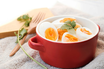 Boiled eggs cut in half, placed in a red bowl, on the tablecloth
