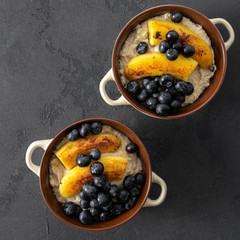 Healthy breakfast with plate oatmeal with fried banana and blueberry on a dark table top view