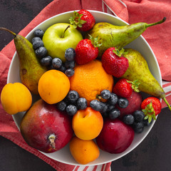 Naklejka na ściany i meble Fruits plate on a dark background top view