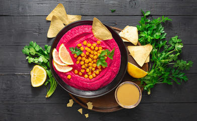 Beetroot hummus in a plate on a dark background top view