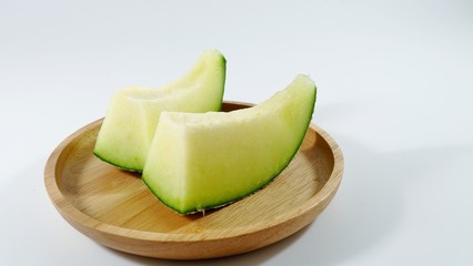 half of melon in wooden plate on white background