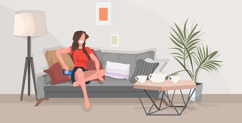girl sitting on couch woman using smartphone communication concept modern living room interior flat full length horizontal
