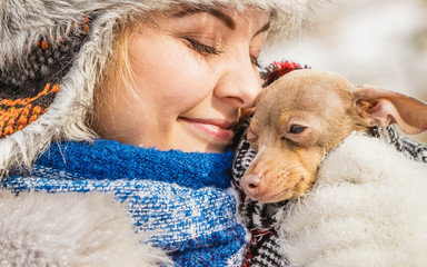 Woman hug warming her little dog in winter