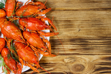 Boiled crayfish in plate on wooden table. Top view