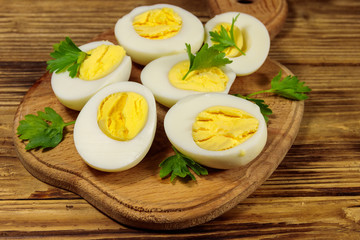 Boiled eggs with parsley on cutting board on a wooden table
