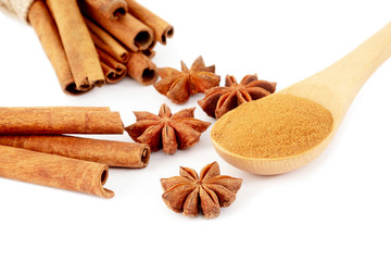 Star anise, Cinnamon sticks and powder in wooden spoon isolated on white background.