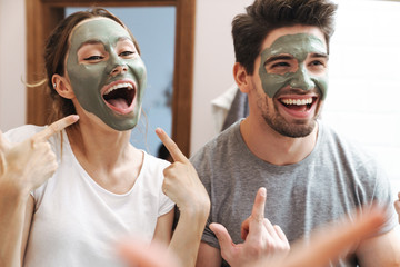 Image of beautiful couple standing in bathroom with face mask