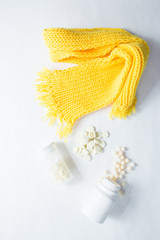 The medicine. The cure for colds and flu. Pills on a white background, plastic packaging for medicine, a yellow knitted scarf for the treatment of a sore throat. Health care. Vitamins