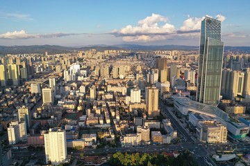 Fototapeta na wymiar Kunming, China - September 13, 2019: Aerial view of Kunming at sunset with the Spring City 66 skyscraper and mall on foreground