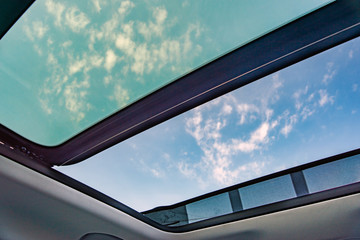 Blue sky through an open car sunroof , view from the passenger compartment,open sunroof look up to...