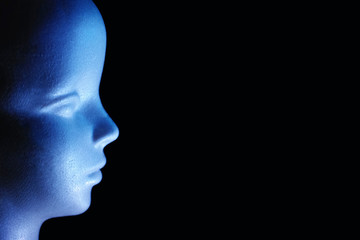 青色の光で照らした発泡スチロール製の人形の横顔と黒いコピースペース　