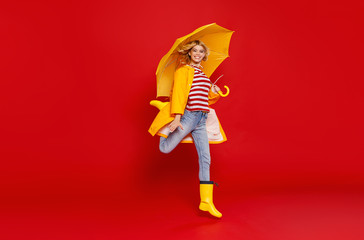 young happy emotional cheerful girl laughing  with yellow umbrella   on colored red background. © JenkoAtaman
