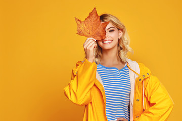 happy emotional girl with autumn leaves on colored yellow background.