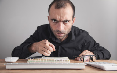 Angry businessman pointing finger at you.