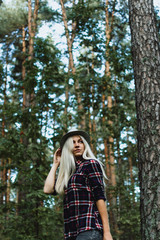 Young adult blonde female in a hat in the woods, selective focus