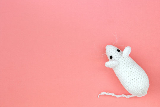 White crocheted rat on a pink background. Mouse symbol 2020 new year. Top view, copy space