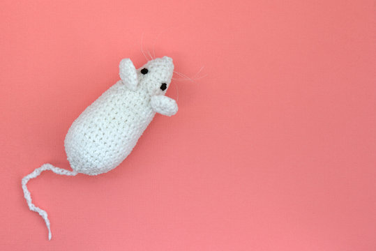 White crocheted rat on a pink background. Mouse symbol 2020 new year. Top view, copy space
