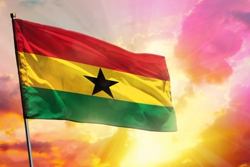 Fluttering Ghana flag on beautiful colorful sunset or sunrise background. Success concept.