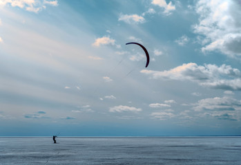 Silhouette of a kitesurfer with a kite on the winter ice. Concepts of freedom and purity of thought.