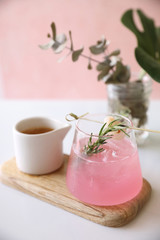 Pink cocktail with rosemary and lychee in pink background