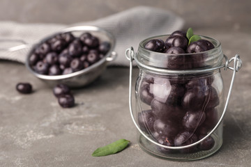 Jar of fresh acai berries on grey stone table, closeup view. Space for text