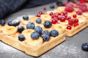 Delicious waffles with fresh berries served on grey table, closeup