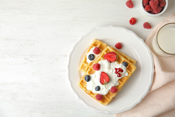 Flat lay composition with delicious waffles and fresh berries on white wooden table. Space for text