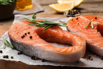 Fresh salmon steaks with spices and rosemary on table, closeup view