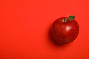 Ripe juicy apple with leaf on red background, top view. Space for text