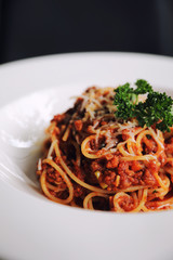 spaghetti Bolognese with minced beef and tomato sauce garnished with parmesan cheese and basil , Italian food