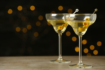 Glasses of Classic Dry Martini with olives on grey table against blurred background. Space for text