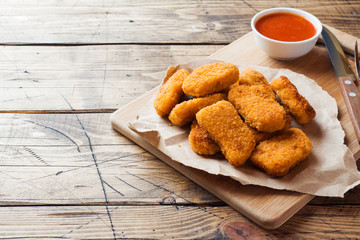 chicken nuggets with tomato sauce on wooden background. Copy space.