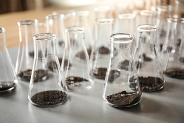 Glassware with soil samples on grey table. Laboratory research