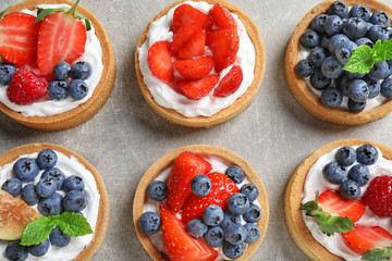 Delicious sweet pastries with berries on grey table, flat lay