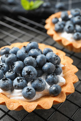 Delicious sweet pastry with berries on cooling rack, closeup