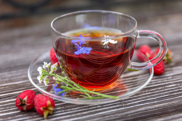 Cup of tea with herbs and fresh berries on a wooden table. Close-up.