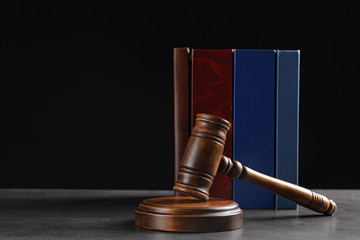 Judge's gavel and books on grey table against black background, space for text. Criminal law concept