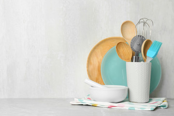 Fototapeta na wymiar Different kitchen utensils on grey table against light background. Space for text