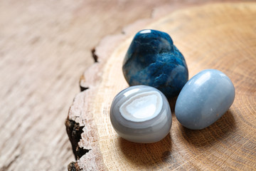 Beautiful blue angelite, grey agate and shattuckite gemstones on wooden stand, closeup - obrazy, fototapety, plakaty