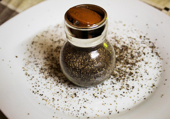 Black pepper in glass kitchen bottle.