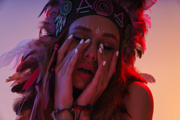 Indian woman in carnival suit isolated with neon lights touching face.